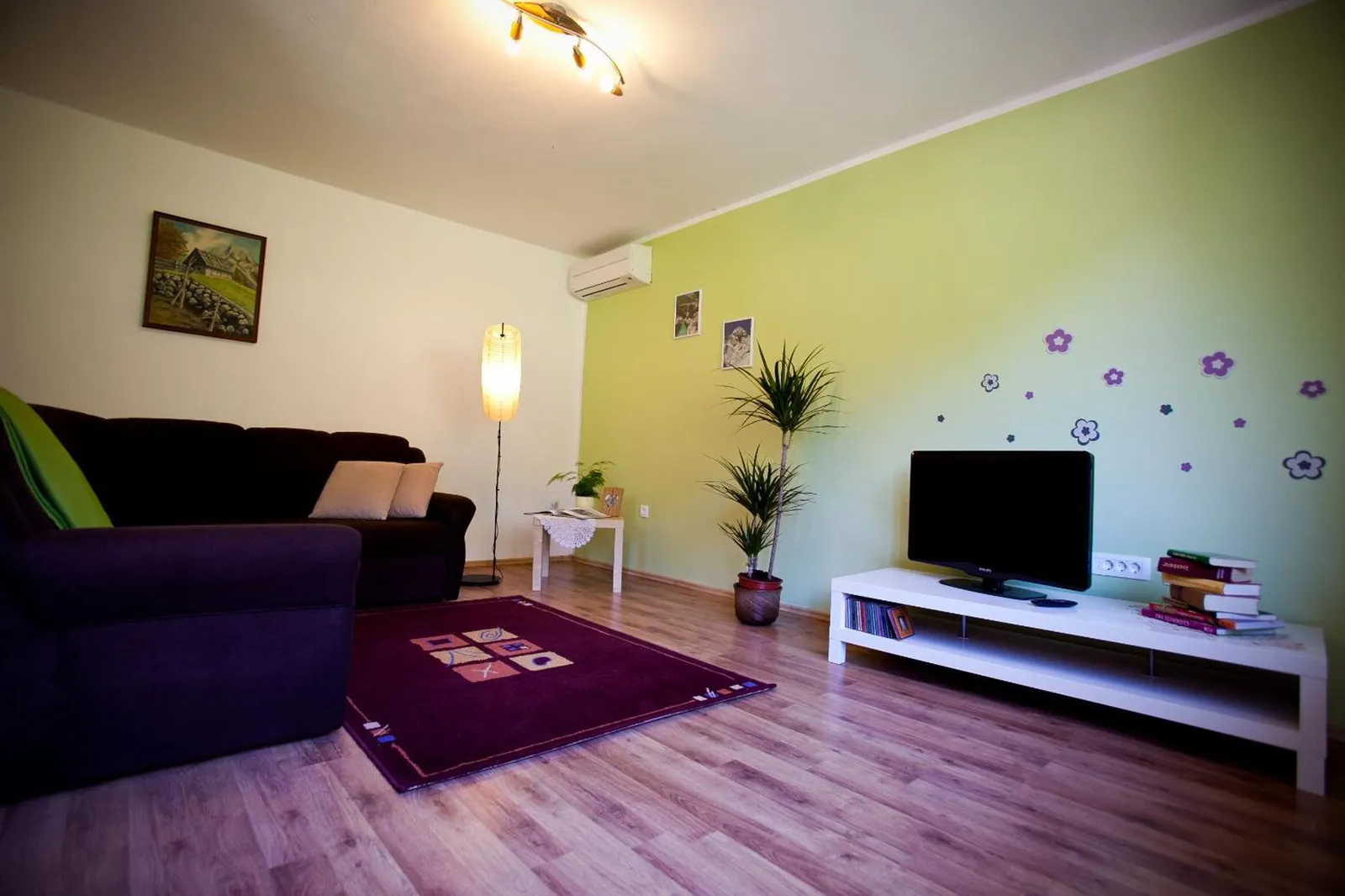Apartma 80: dnevna soba z zelenimi stenami in temnim kavčem